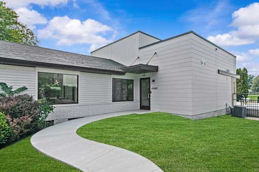 A modern building with a grey exterior and a black roof at Park On Canal Apartments - Clinton Twp, MI Apartments, Michigan