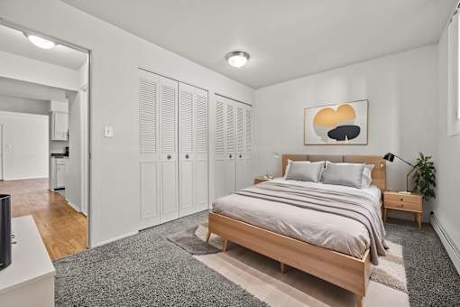A bedroom with a bed, a nightstand, and a plant.