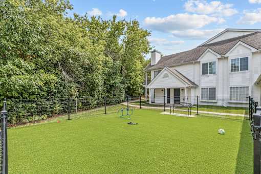 A white house with a green lawn and a playground in front.