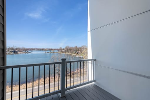 A balcony overlooks a body of water with boats and trees in the distance.