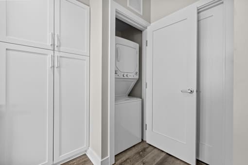 A white cabinet with a door open revealing a white dishwasher and washing machine.