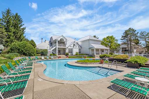 A large swimming pool with lounge chairs and a building in the background.