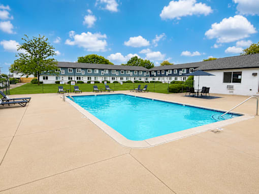A large swimming pool in front of a building with a white exterior.