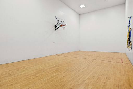 A basketball hoop is mounted on a wall in a room with a wooden floor.
