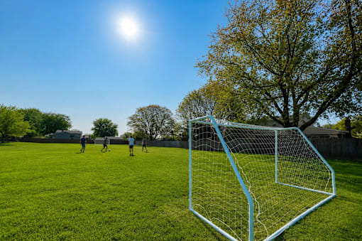 A soccer game is being played in a field with a goal on the right. at Park On Canal Apartments - Clinton Twp, MI Apartments, Clinton Twp, MI, 48038