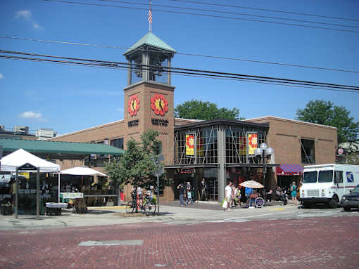 A brick building with a clock tower in the middle of a street.