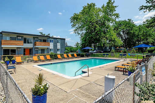 A pool area with a fence and a building in the background.
