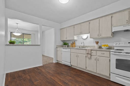 A kitchen with white appliances and wooden floors.