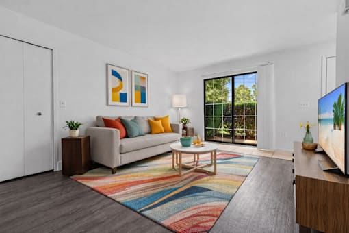 A living room with a grey couch, a coffee table, a rug, and a painting on the wall.