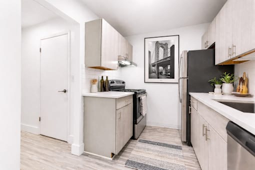 A kitchen with a black refrigerator and a black and white framed picture on the wall.