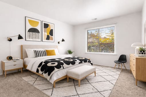 A bedroom with a large bed, a chair, and a window with blinds.