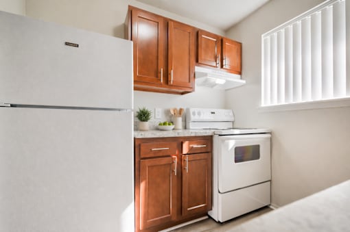 A white refrigerator is in a kitchen with wooden cabinets.