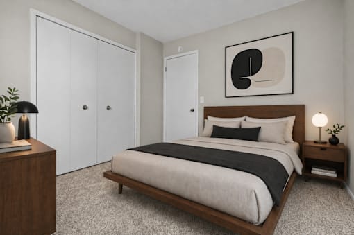 A bedroom with a large bed, a wooden nightstand, and a framed picture on the wall.