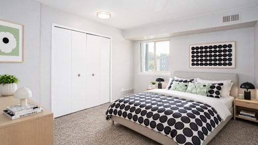 A bedroom with a bed, nightstand, and a plant on the dresser.
