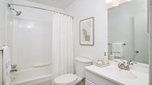A white bathroom with a toilet, sink, and shower.