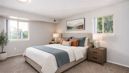 A bedroom with a bed, nightstand, and a painting on the wall.