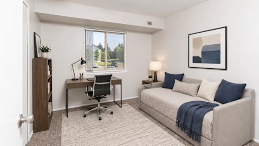 A room with a desk, chair, and couch.