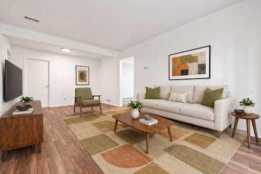A living room with a white couch and a wooden floor.