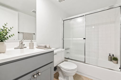 A white bathroom with a toilet, sink, and shower.