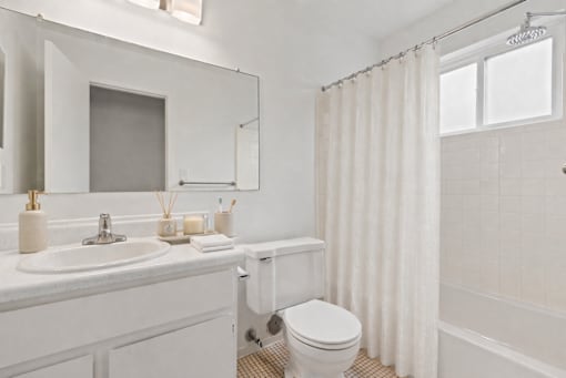 A white bathroom with a toilet, sink, and shower.
