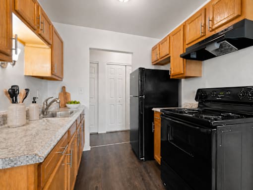 A kitchen with black appliances and wooden cabinets.