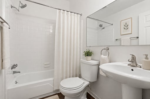 A white bathroom with a toilet, sink, and bathtub.
