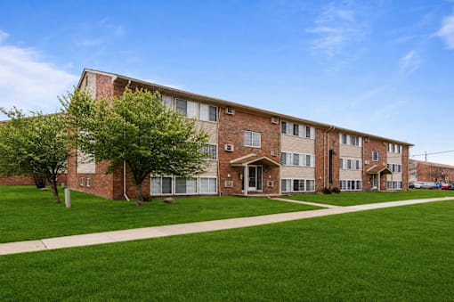 A large brick building with a green lawn in front.