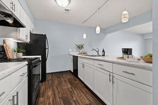 A kitchen with black appliances and white cabinets.