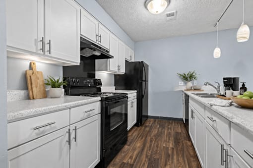 A kitchen with black appliances and white cabinets.