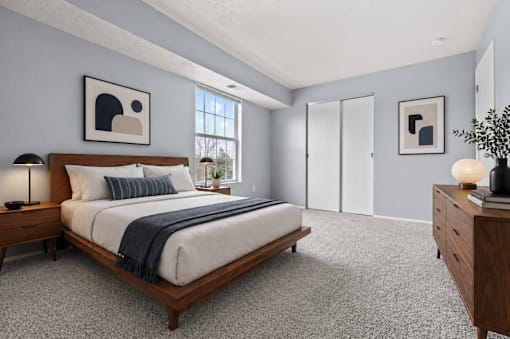 A bedroom with a bed, nightstands, and a plant.