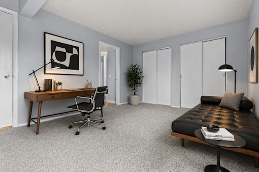 A modern bedroom with a black leather bed and a desk with a chair.