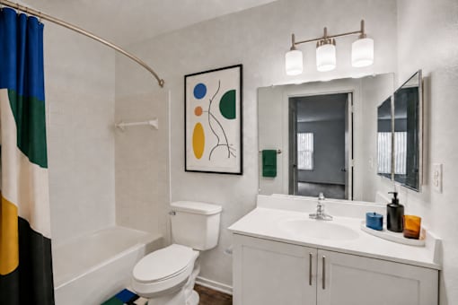 A bathroom with a white toilet, a white sink, and a mirror.