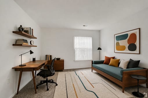 A room with a desk, a couch, and a painting on the wall.