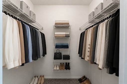 A walk in closet with clothes and shoes.