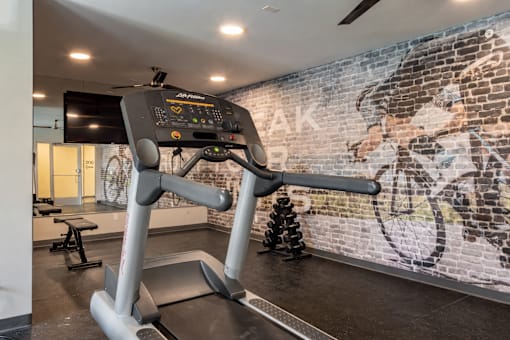 A treadmill in a gym with a brick wall in the background.