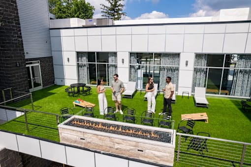 A group of people are gathered around a fire pit on a patio.