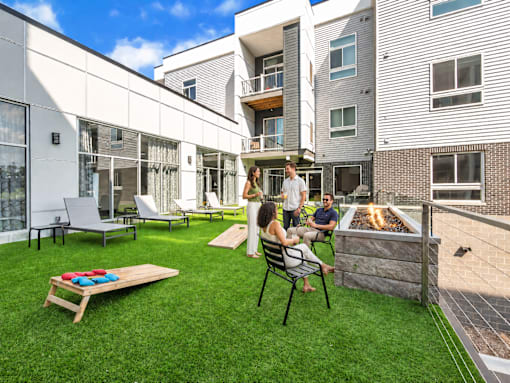 A group of people are sitting on a patio with a fire pit.