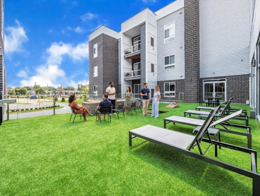 A group of people are gathered on a patio in front of a building.