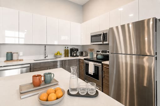 A modern kitchen with a stainless steel refrigerator and white cabinets.