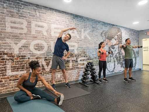 A group of people exercising in a gym with a brick wall that says "BREAK YOUR".