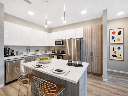 A modern kitchen with a white countertop and stainless steel appliances.