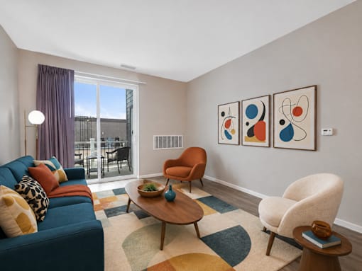 A living room with a blue couch, a wooden coffee table, and a large window with a view of the city.