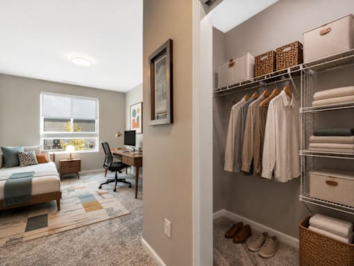 A bedroom with a bed, desk, chair, and closet.