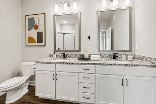 A bathroom with a toilet, sink, and mirror.