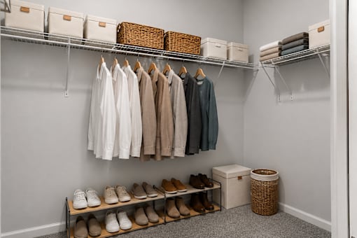 A closet with clothes and shoes neatly organized on shelves and racks.