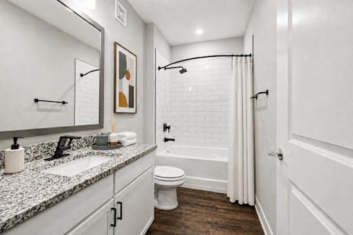 A white bathroom with a toilet, sink, and a shower.