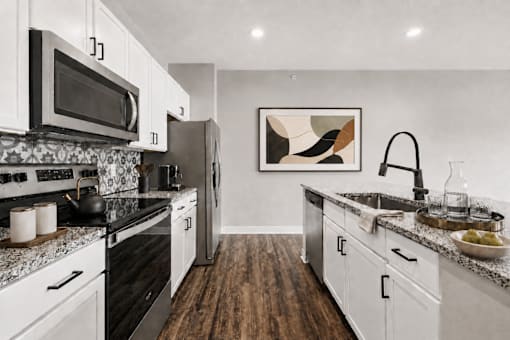 A modern kitchen with white cabinets and a black stove top.