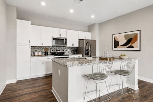 A kitchen with white cabinets and a granite countertop.