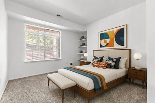 A bedroom with a bed, nightstands, and a painting on the wall.