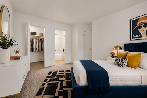 A bedroom with a large bed and a painting of a woman wearing a hat.